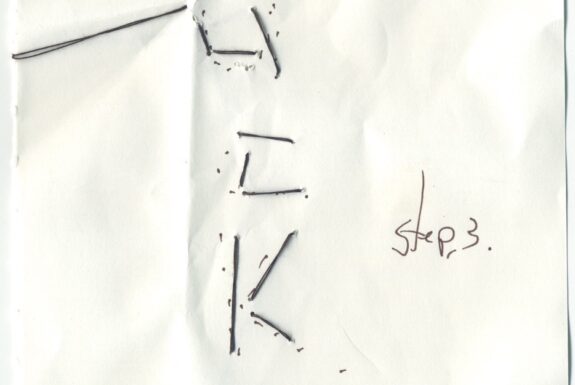 Notebook page from Step 2 with the word 'Lucky' in black thread and 'Step 3' in fine black ink